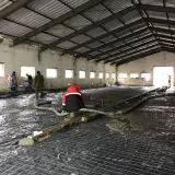 Pracownicy wylewają beton na zbrojenie wewnątrz hali.
