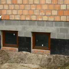 Fundamenty starego domu z oknami i izolacją przeciwwilgociową. Czy ocieplać fundamenty w starym domu? Rozważamy termoizolację.