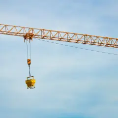 Żółty dźwig budowlany z koszem na beton. Zastanawiasz się, ile waży dźwig?