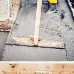Wylewanie betonu na budowie. Zastanawiasz się, ile cementu na betoniarkę 250l? Drewniane szalunki wypełnione świeżą masą.