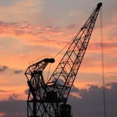 Sylwetka dźwigu na tle zachodzącego słońca. Ten resurs dźwigu, co to jest, to potężna konstrukcja gotowa do pracy.