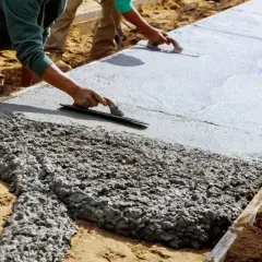 Robotnicy wygładzają świeżą wylewkę betonową. Zastanawiasz się, na ile starczy 25 kg wylewki?
