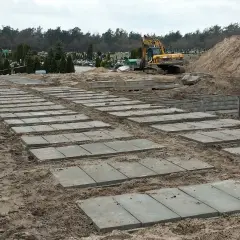 Przygotowanie terenu na cmentarzu, gdzie układane są płyty betonowe. Zastanawiasz się, ile kosztuje fundament pod pomnik? Tu widać początek prac.