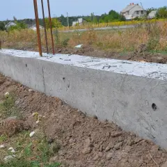 Nowy betonowy fundament z wystającymi prętami zbrojeniowymi, gotowy do połączenia ze starym fundamentem.