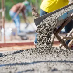 Beton wylewany z rynny na placu budowy. Kluczowe dla prawidłowego wykonania prac jest to, jak obliczyć ilość betonu na wylewkę.