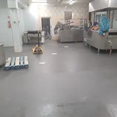 Nowa, szara wylewka betonowa w kuchni przemysłowej schnie, czekając na dalsze prace.