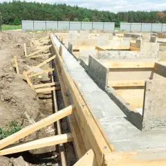 Budowa fundamentów pod dom szkieletowy. Betonowe ławy i szalunki drewniane tworzą solidną podstawę.