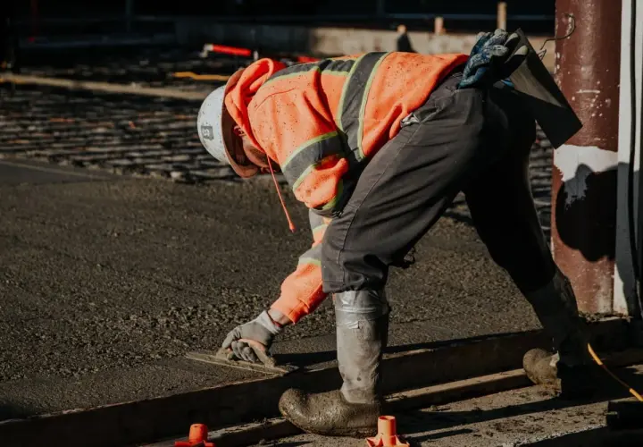 Robotnik w pomarańczowej kamizelce wygładza świeżą wylewkę. Zastanawiasz się, ile worków wylewki na 1m2 potrzeba?