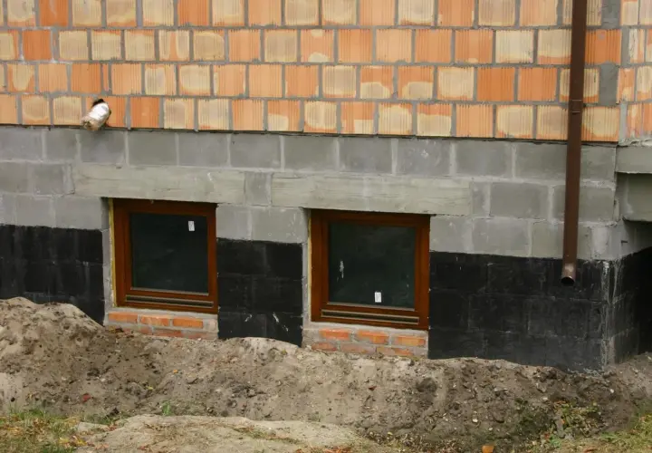 Fundamenty starego domu z oknami i izolacją przeciwwilgociową. Czy ocieplać fundamenty w starym domu? Rozważamy termoizolację.