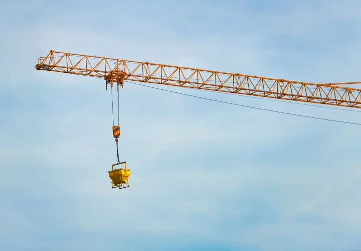 Żółty dźwig budowlany z koszem na beton. Zastanawiasz się, ile waży dźwig?