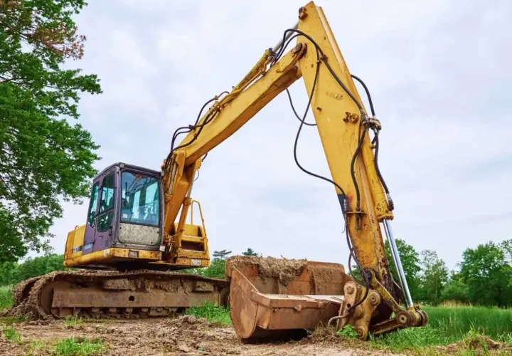 Żółta koparka gąsienicowa na placu budowy. Zastanawiasz się, jaki olej hydrauliczny do koparki będzie najlepszy?