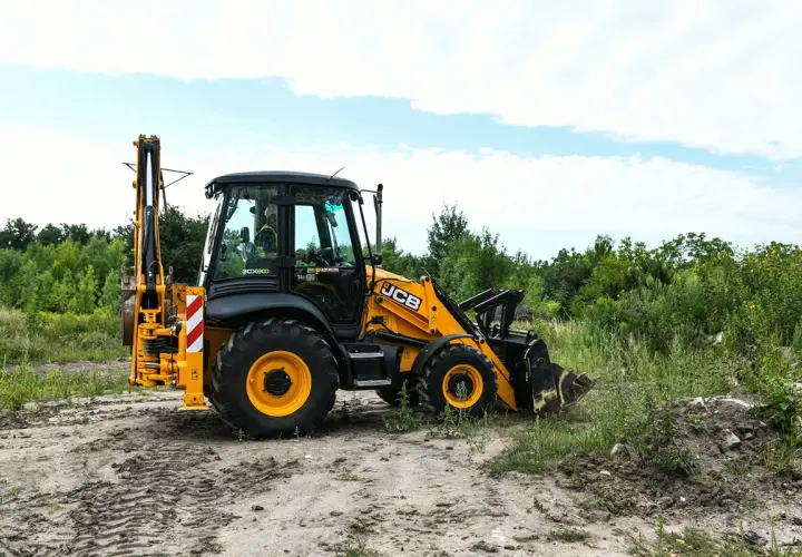 Żółta koparko-ładowarka JCB na placu budowy. Uprawnienia na koparko ładowarkę do czego uprawniają? Do obsługi maszyn budowlanych, takich jak ta.