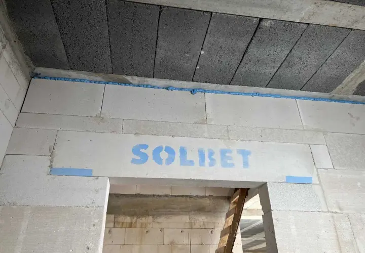 Piana montażowa w szczelinie między stropem a ścianą z bloczków z napisem "SOLBET".