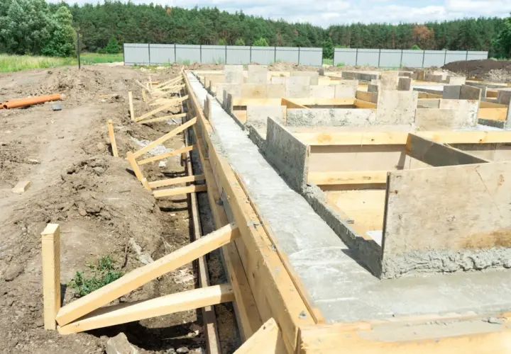 Budowa fundamentów pod dom szkieletowy. Betonowe ławy i szalunki drewniane tworzą solidną podstawę.