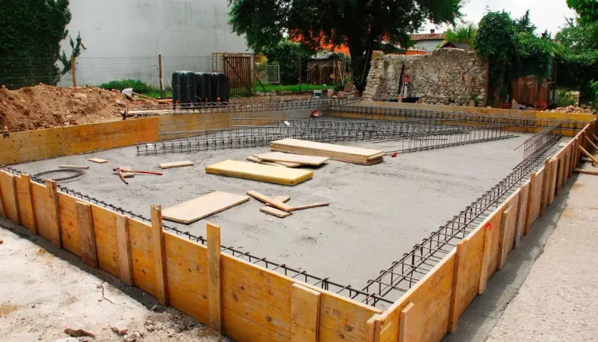 Budowa fundamentów: szalunki drewniane, zbrojenie i wylana płyta betonowa.