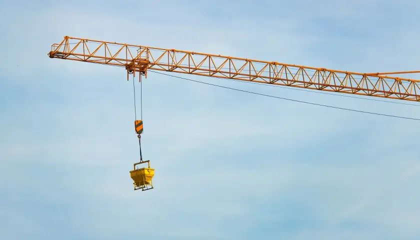 Żółty dźwig budowlany z koszem na beton. Zastanawiasz się, ile waży dźwig?