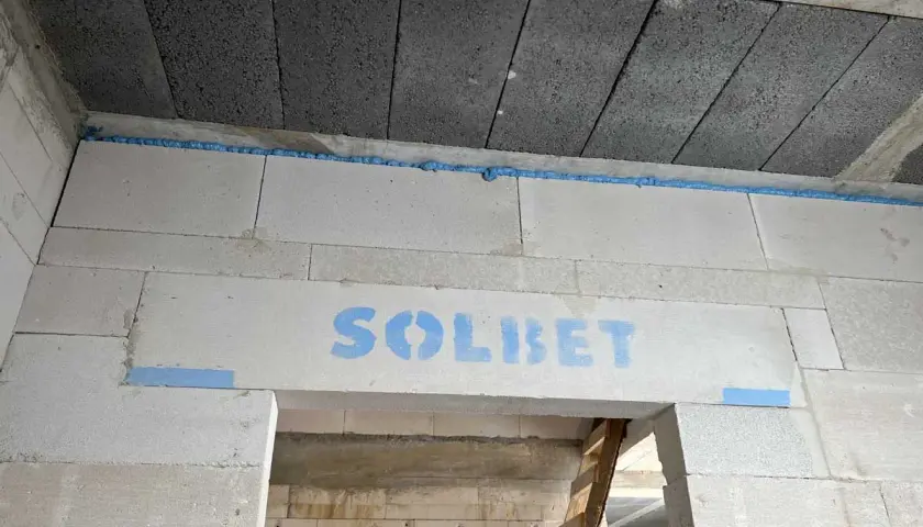 Piana montażowa w szczelinie między stropem a ścianą z bloczków z napisem "SOLBET".