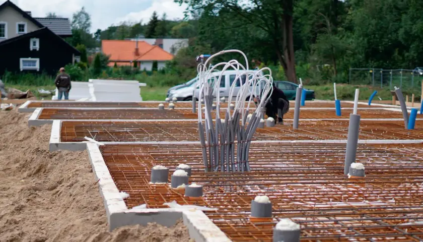 Budowa fundamentów domu: zbrojenie, rury i izolacja.