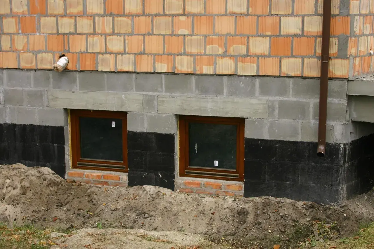 Fundamenty starego domu z oknami i izolacją przeciwwilgociową. Czy ocieplać fundamenty w starym domu? Rozważamy termoizolację.