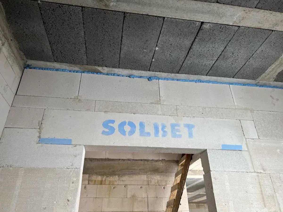 Piana montażowa w szczelinie między stropem a ścianą z bloczków z napisem "SOLBET".