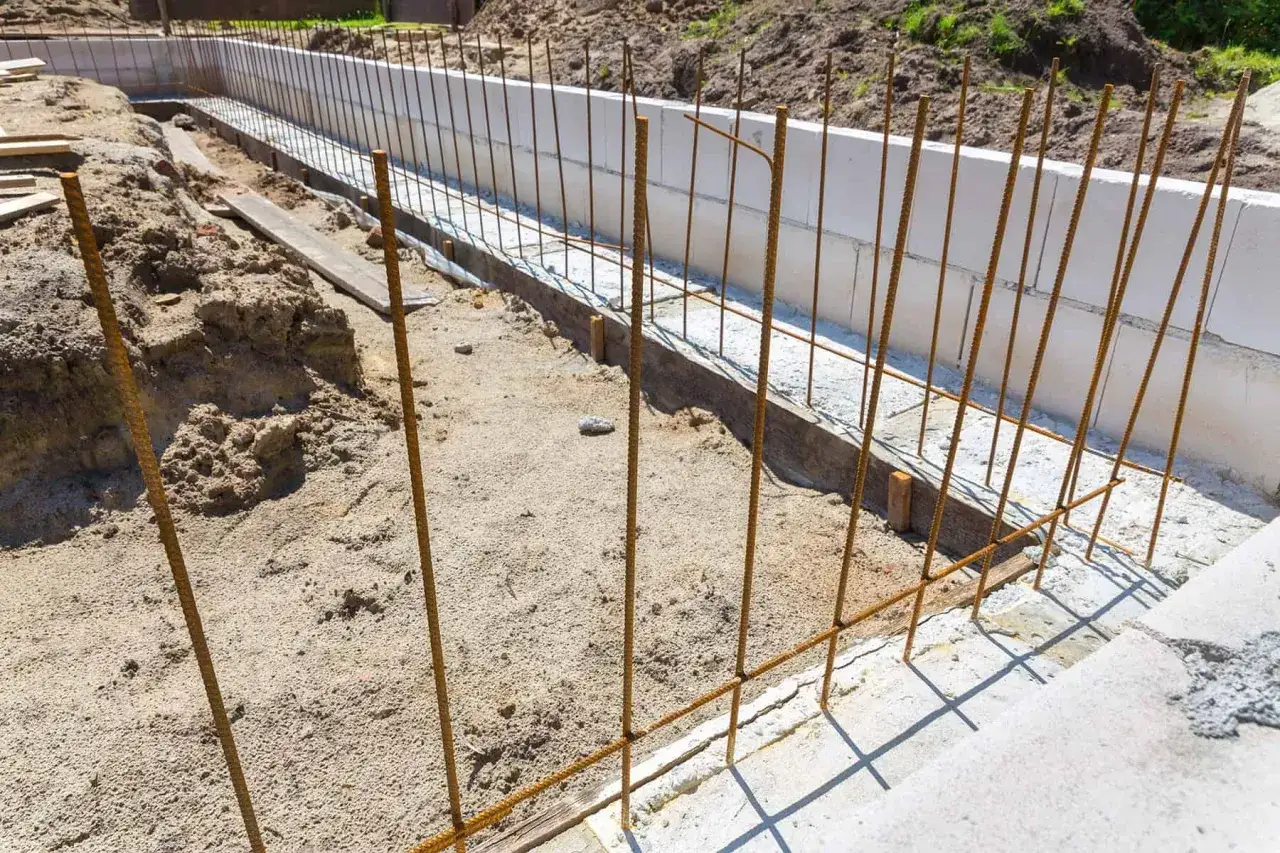 Widoczne zbrojenie na fundamenty, przygotowane do zalania betonem. Stalowe pręty tworzą siatkę wzmacniającą konstrukcję.