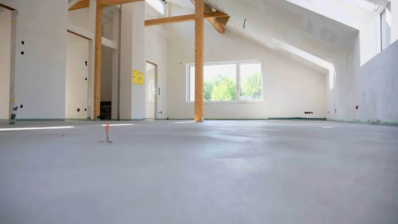 Nowe wnętrze z drewnianymi belkami i oknem. Zastanawiasz się, ile kosztuje metr kwadratowy wylewki?
